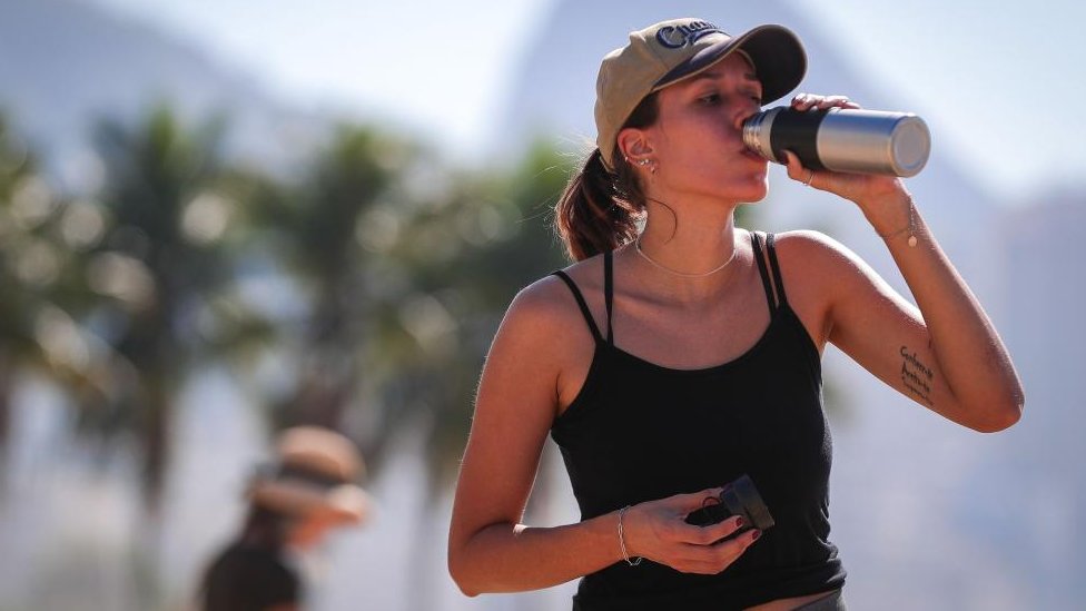 Klimatske promene: Šta su El Ninjo i La Ninja i kako utiču na vremenske prilike 7 A woman drinks water on Copacabana Beach in Rio de Janeiro, Brazil, during a heatwave