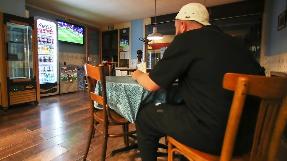 Da li je jedenje pred televizorom zaista toliko štetno po vas 2 Muškarac okrenut leđima jede za stolom i gleda u televizor u baru