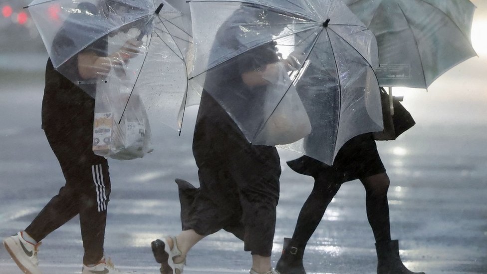 Tajfun pogodio Japan, nastradalo šestoro ljudi 5 Troje ljudi prelazi ulicu u Kagošimi sa kišobranima uz jak vetar