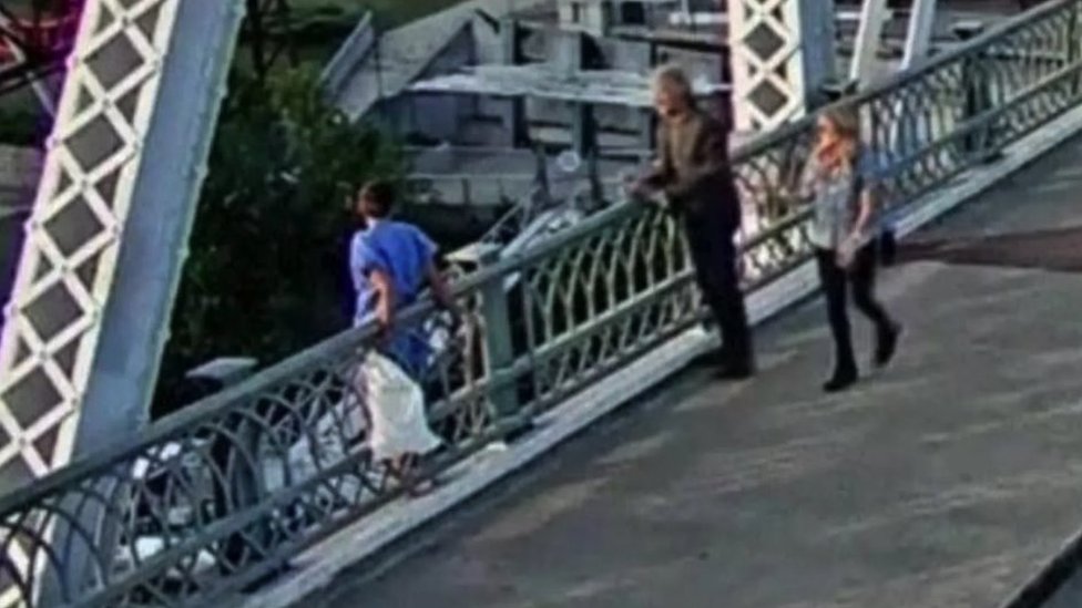 Džon Bon Džovi pomogao ženi koja je htela da skoči s mosta 1 Žena u plavoj majici stoji na mostu a Bon Džovi pokušava da razgovara s wom