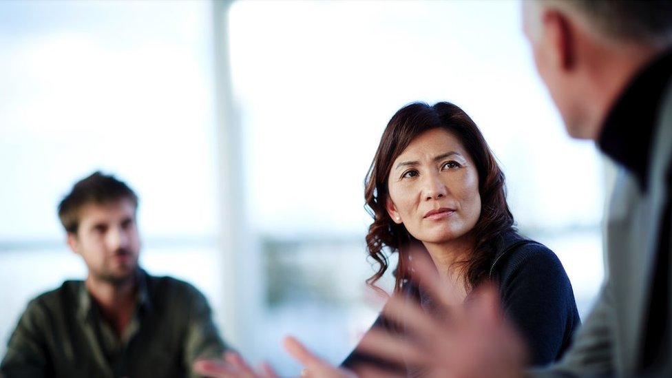 Zašto žene ređe postavljaju pitanja iz publike? 4 Žena sluša muškarca koji govori dok drugi muškarac gleda