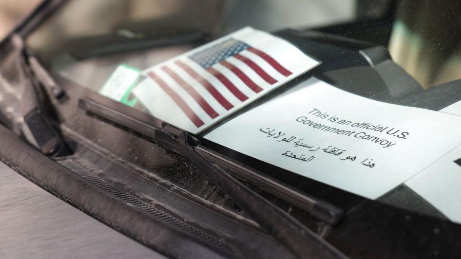 Prozor automobila na kom je natpis na arapskom i engleskom o zvaničnom američkom konvoju