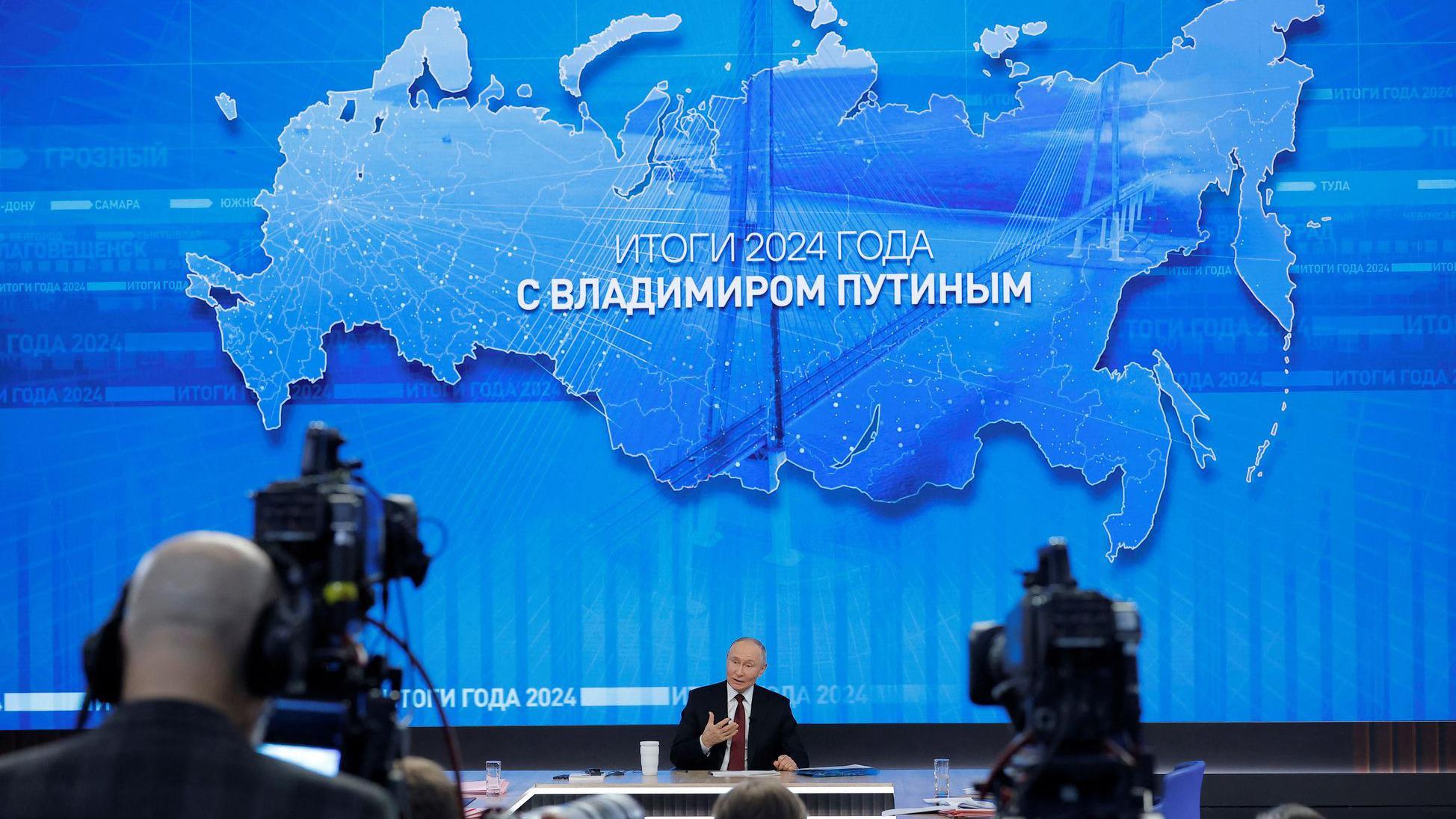 Vladimir Putin za velikim stolom u studiju na godišnjoj konferenicji za novinare