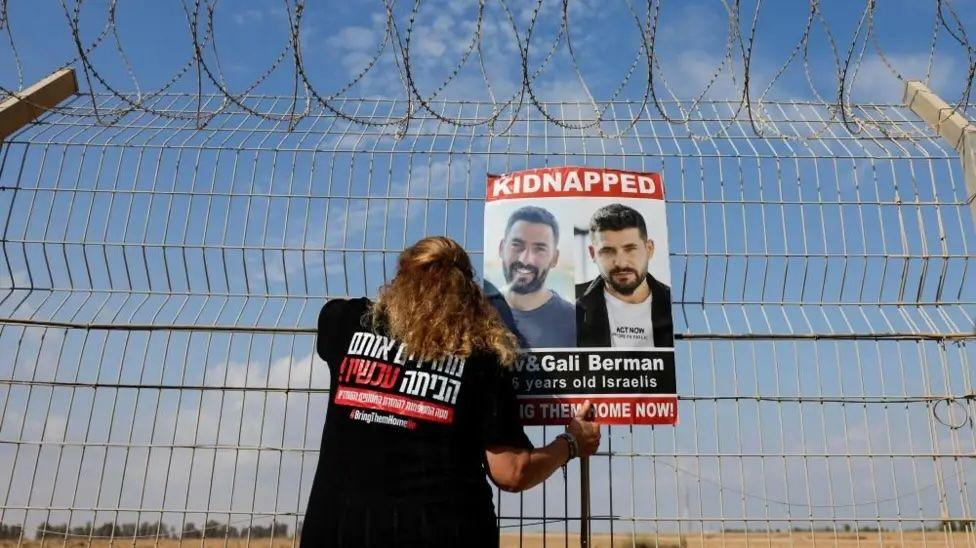 Kako glasi sporazum o primirju u Gazi i može li da potraje 5 A woman attaches a poster to a fence, showing the faces of two men with the word 'Kidnapped' at the top