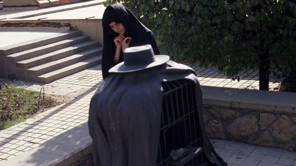 Remek-dela koja mogu da se vide samo u Teheranu 13 A young woman, fully covered in Islamic chador, viewing Rene Magritte's sculpture 'The Healer' in the grounds of Tehran Museum of Contemporary Art