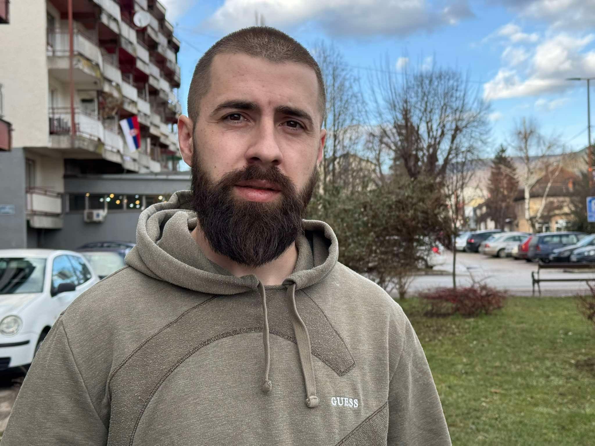 Zašto se nekad smejemo na sahranama 5 Muškarac sa bradom u zelenom duksu sa kapuljačom stoji napolju i gleda u kameru