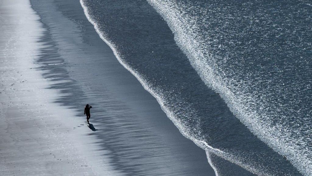 Čovek hoda sam na plaži