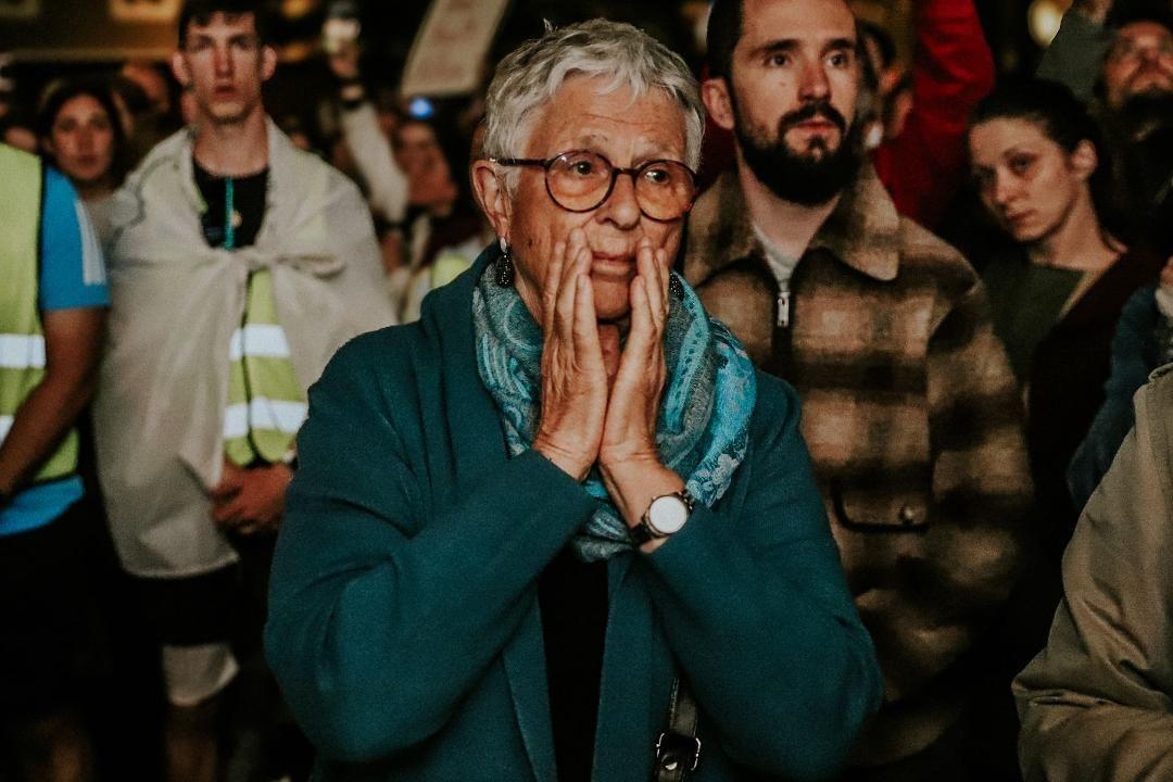 Starija seda žena drži se rukama za lice