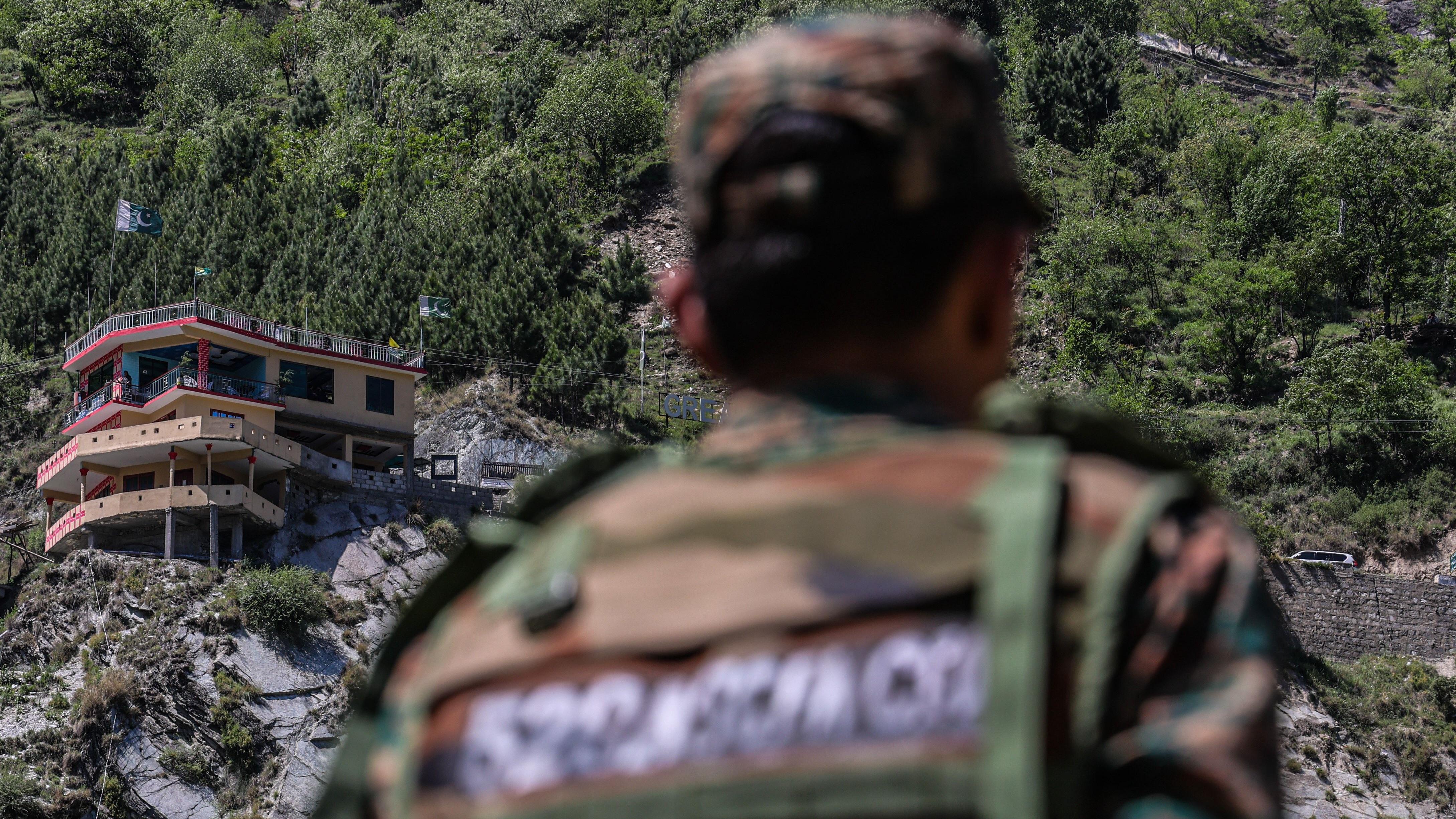 Zašto su u Kašmiru izbili neredi 4 Pakistanska zastava i zgrade dok ih gleda vojnik u selu Simari na indijskoj strani Linije kontrole