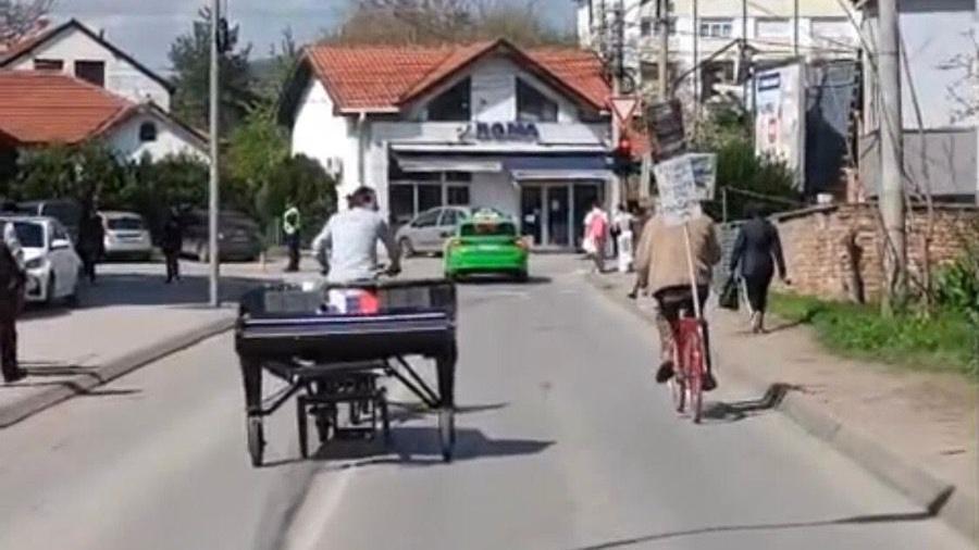 Kako su protesti u Srbiji inspirisali dvojicu italijanskih muzičara 3 Davide Martelo vozi biciklo i vuče klavir, do njega na bicikli stariji Nišlija koji mu pomaže da se snađe u gradu