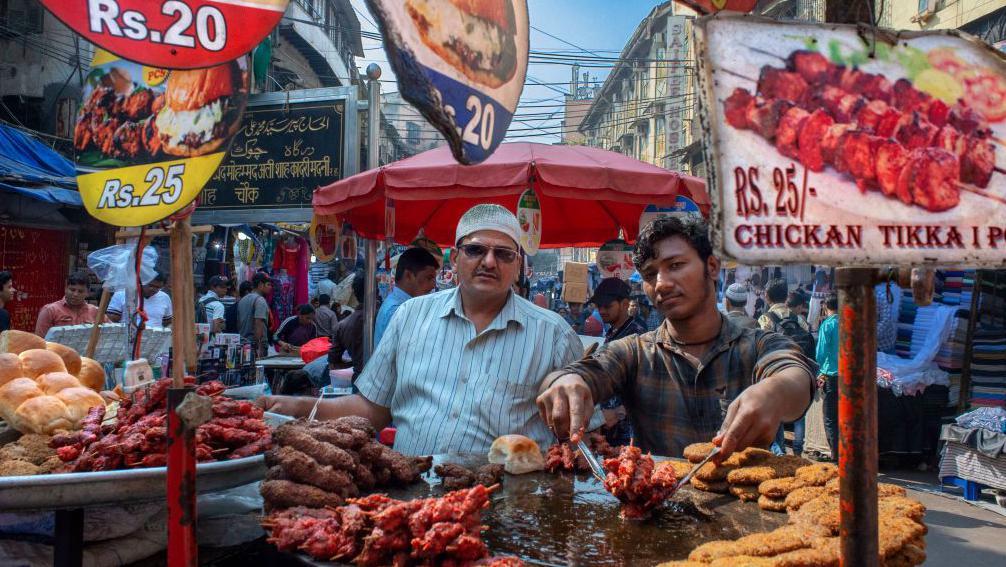 Čeka li nas decenija rekordnih cena hrane 4 Dva muškarca stoje pored velikih metalnih štandova sa kuvanim mesom, u Mumbaiju, 2022.