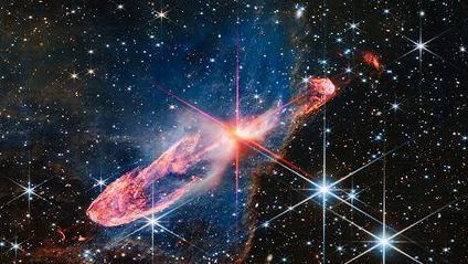 Naučnici se utrkuju da otkriju zašto postoji svemir 2 Mala jarko crvena zvezda osvetljava gusti vrtložni prsten gasa oko sebe, a u pozadini je polje zvezda