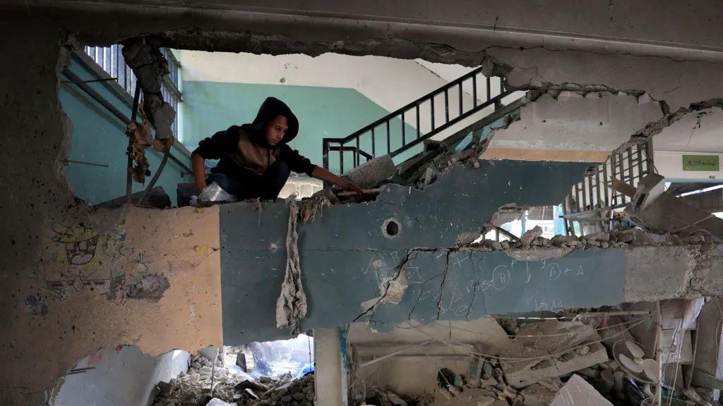 Desetine poginulih u napadu Izraela na izbegličko sklonište u školi 2 Dečak gleda štetu napravljenu u vazdušnom napadu na školu u kojoj su bili smešteni raseljeni Palestinci