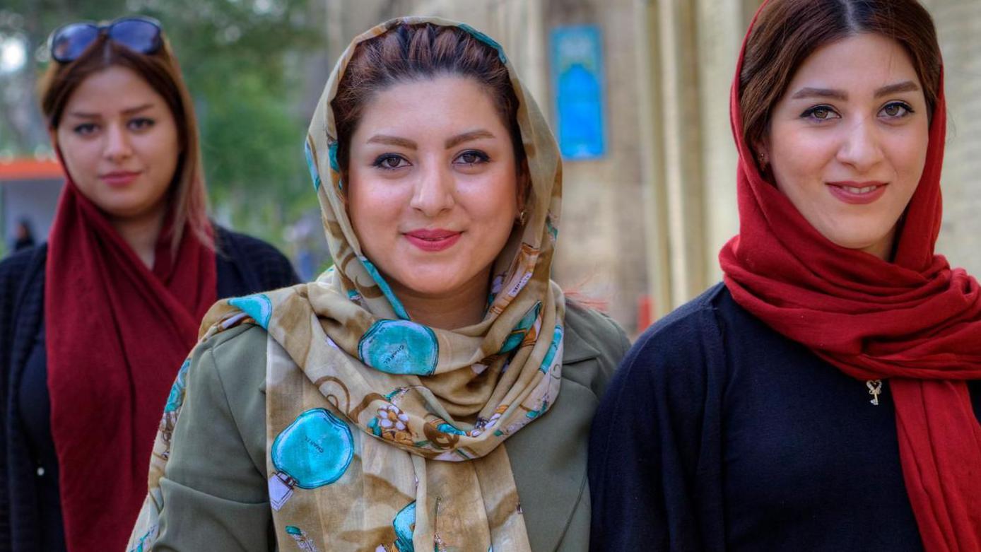 Izbor 'partnera nižeg statusa': Da li je to novi standard obrazovanih žena 5 Mlade Iranke, obučene u hidžab, šetaju gradskom ulicom sa mobilnim telefonima u rukama.