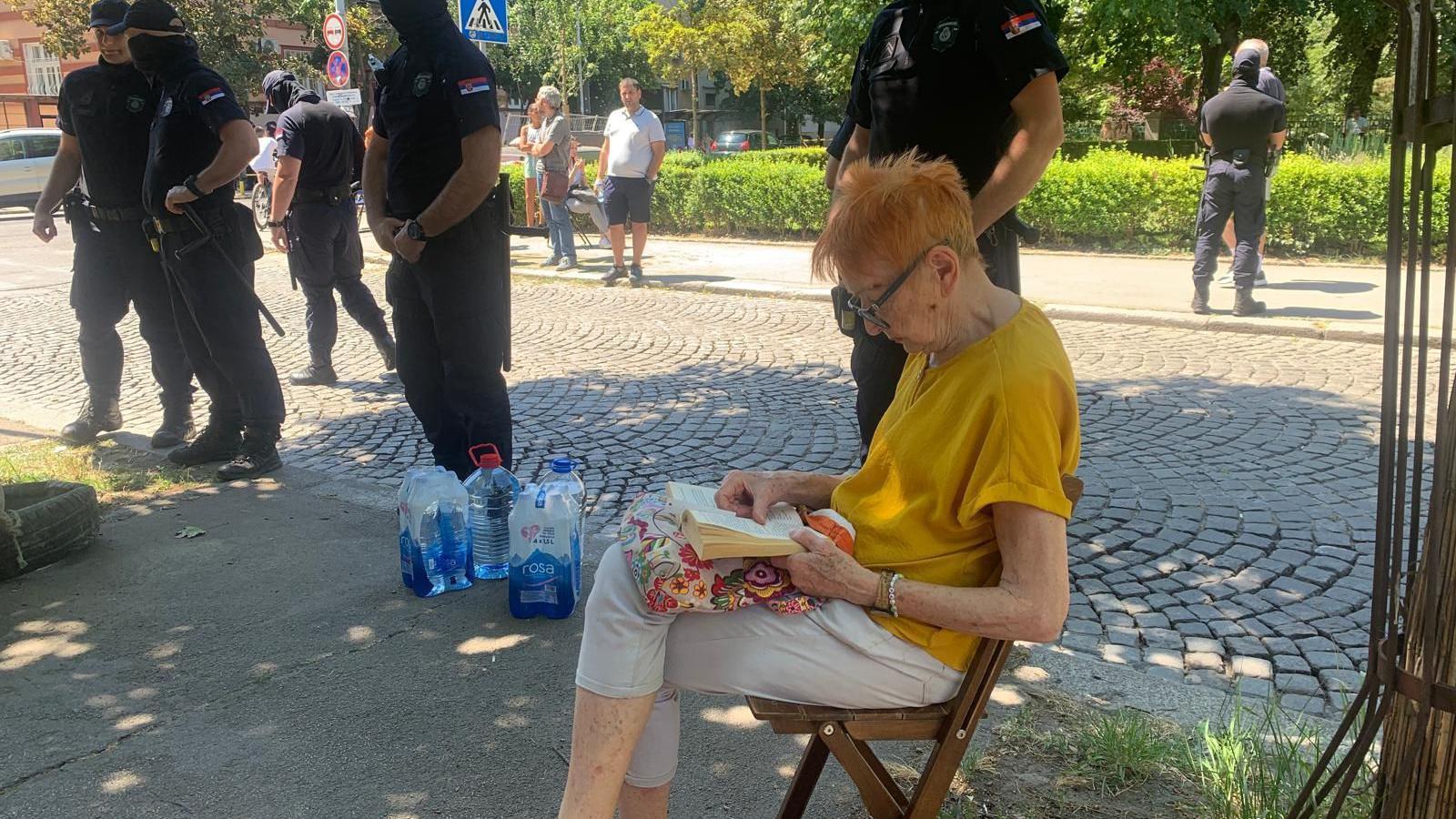 Policija uklonila deo blokada širom Srbije, nova okupljanja u Beogradu 3 Baka sedi na trotoaru i čita knjigu, pored nje policija