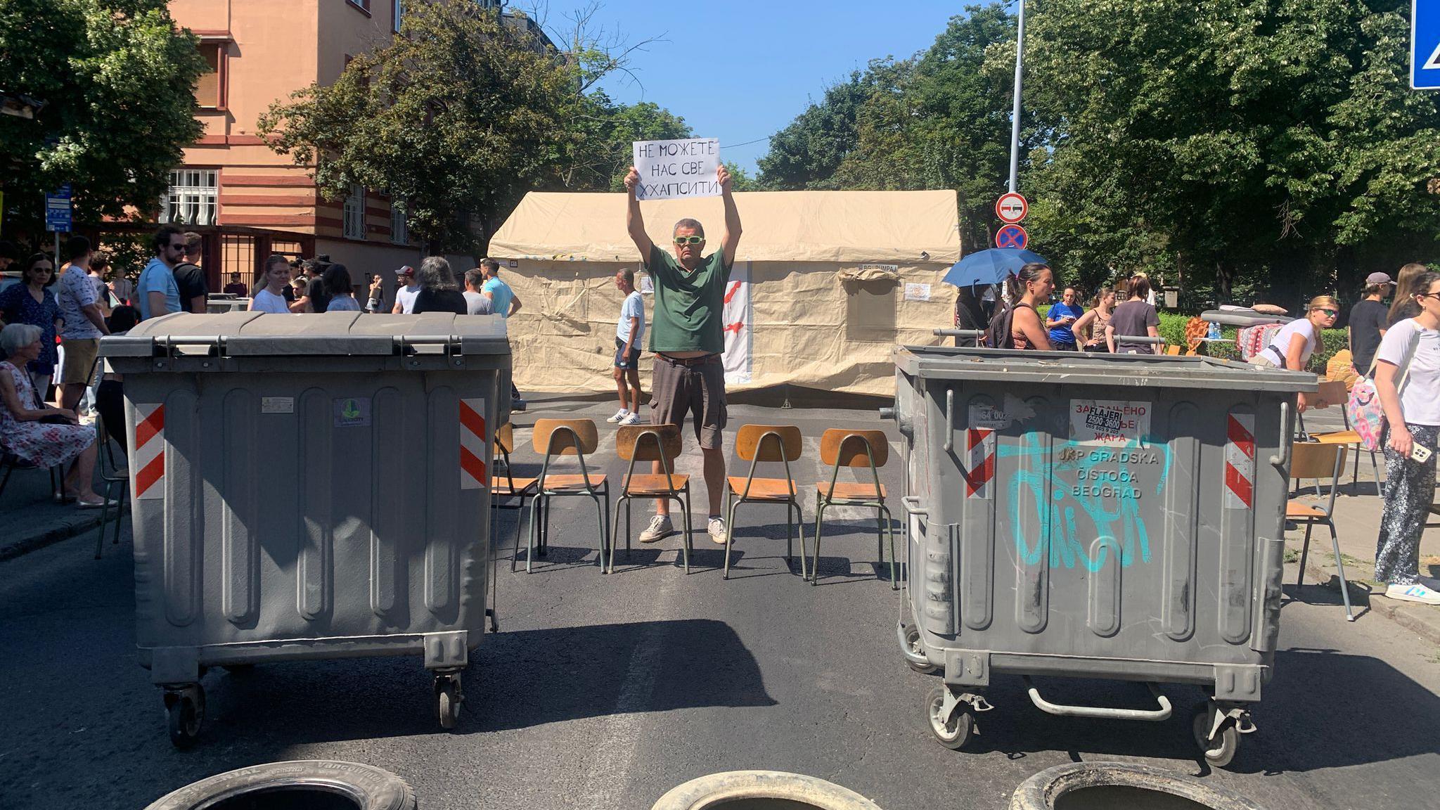 Policija uklonila deo blokada širom Srbije, nova okupljanja u Beogradu 1 Muškarac stoji sa transparentom na sred ulice okružen kontejnerima tokom blokade