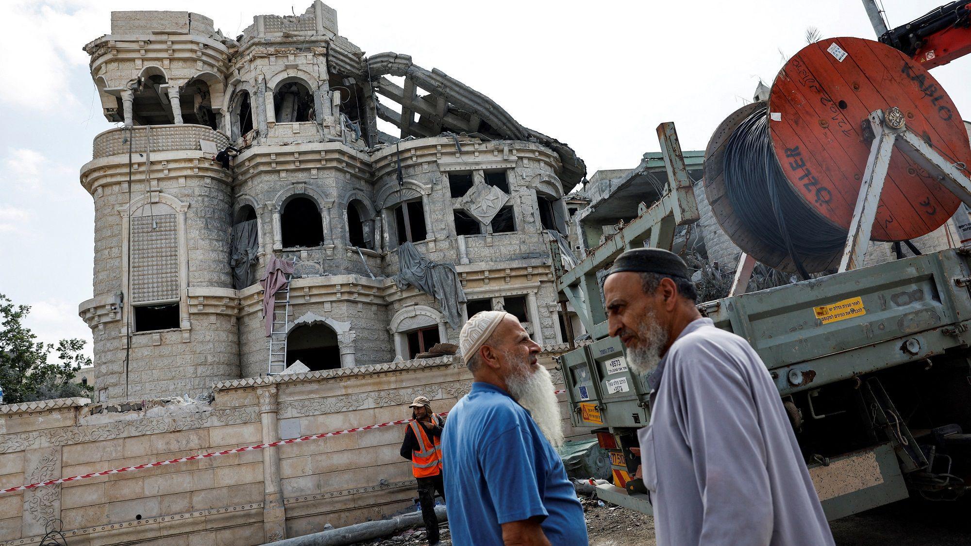 Raketni napadi Izraela i Irana: Izraelci tvrde da 'kontrolišu nebo nad Teheranom' 4 Dva muškarca prolaze pored pogođene zgrade u Izraelu