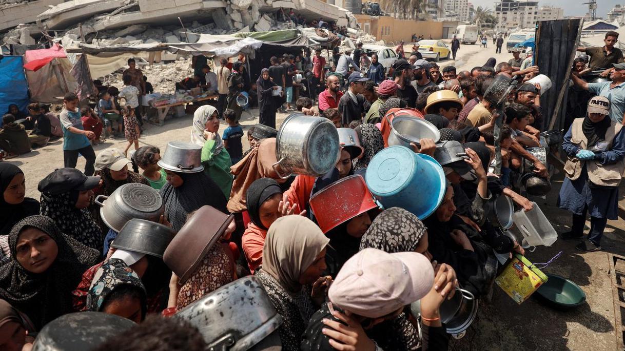 Izraelske organizacije optužuju Tel Aviv za genocid nad Palestincima 1 Grupa ljudi sa praznim šerpama čeka da primi humanitarnu pomoć