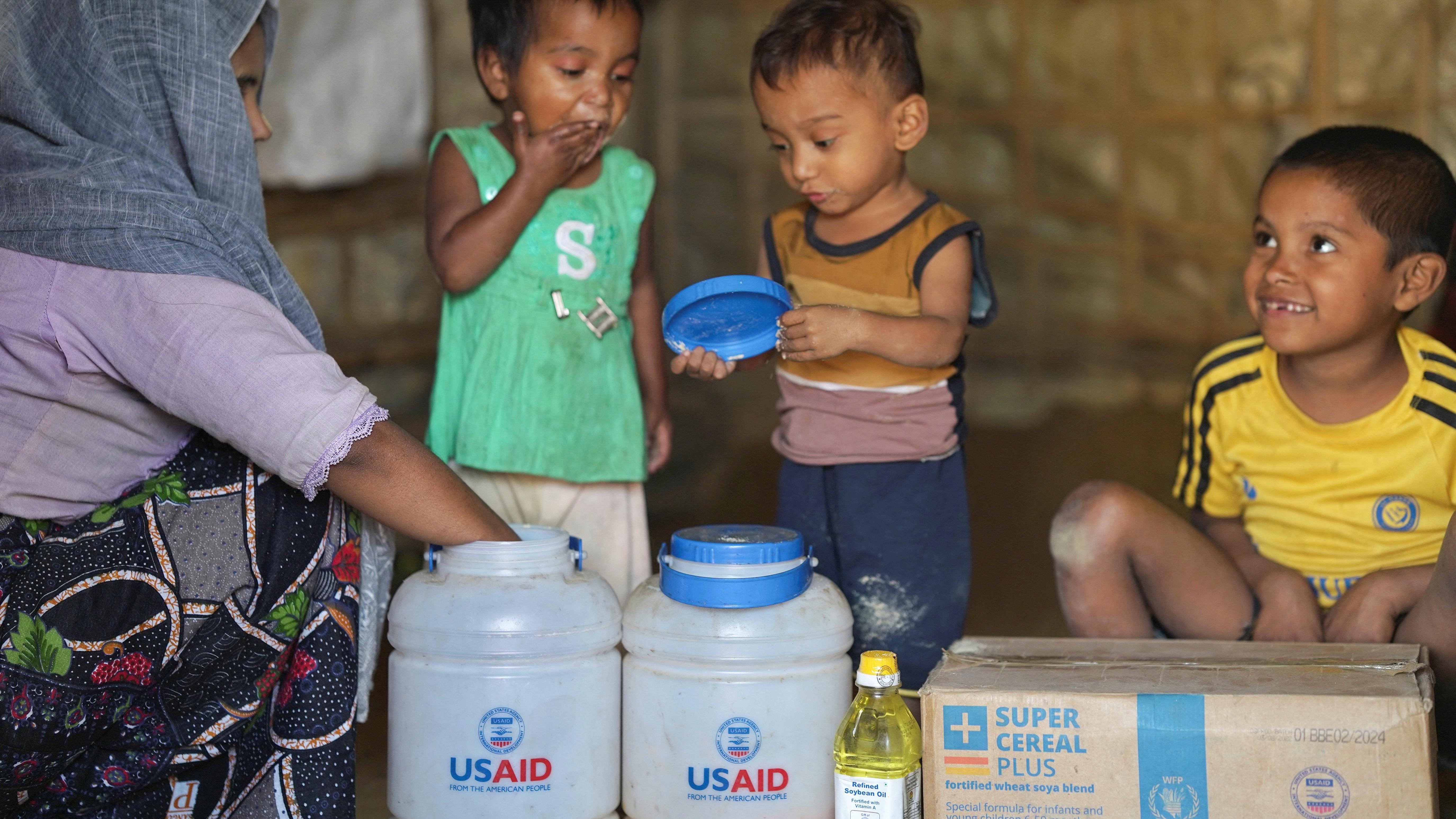 Oko14 miliona ljudi može da umre zbog Trampovog smanjenja pomoći, pokazuje izveštaj 1 Rohingya children eat from jars with the USAID logo on them, at a refugee camp in Cox's Bazar, Bangladesh