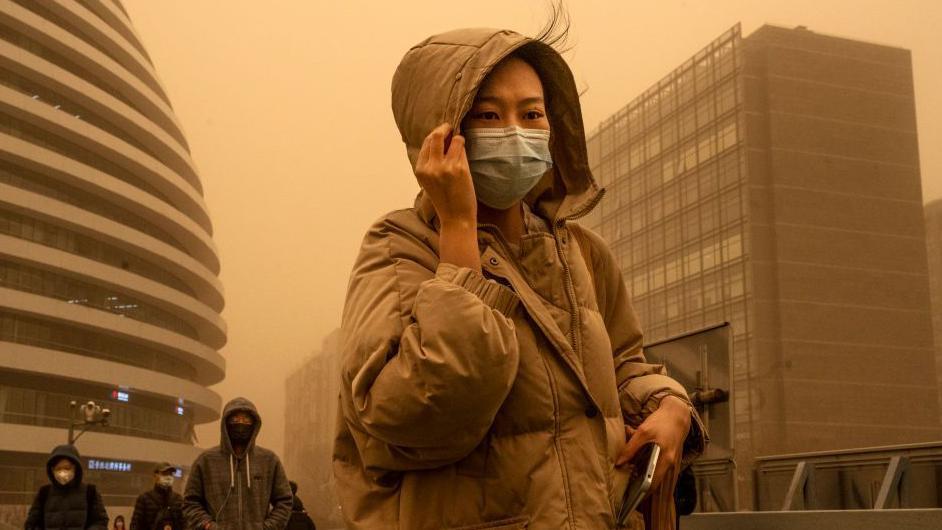 kineskinja sa maskom preko lica zbog peščane oluje