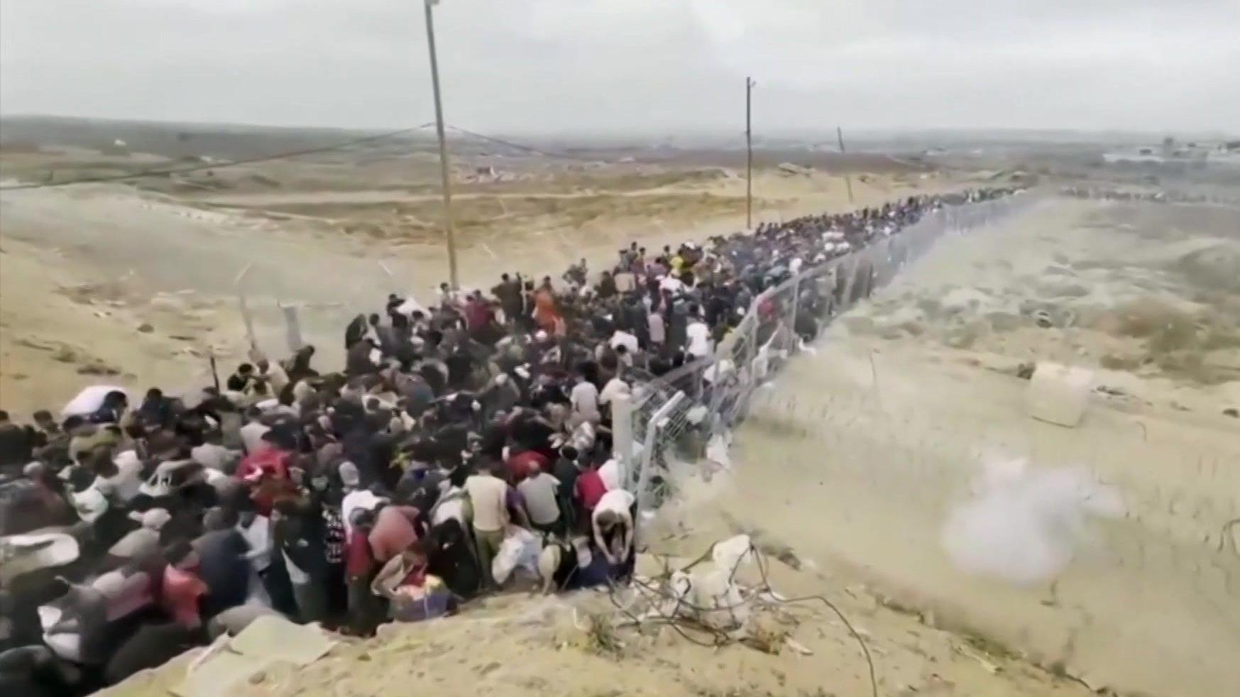 Dostavljeni snimci prikazuju duge redove Palestinaca u potrazi za pomoći kroz ograđeni prostor žicom