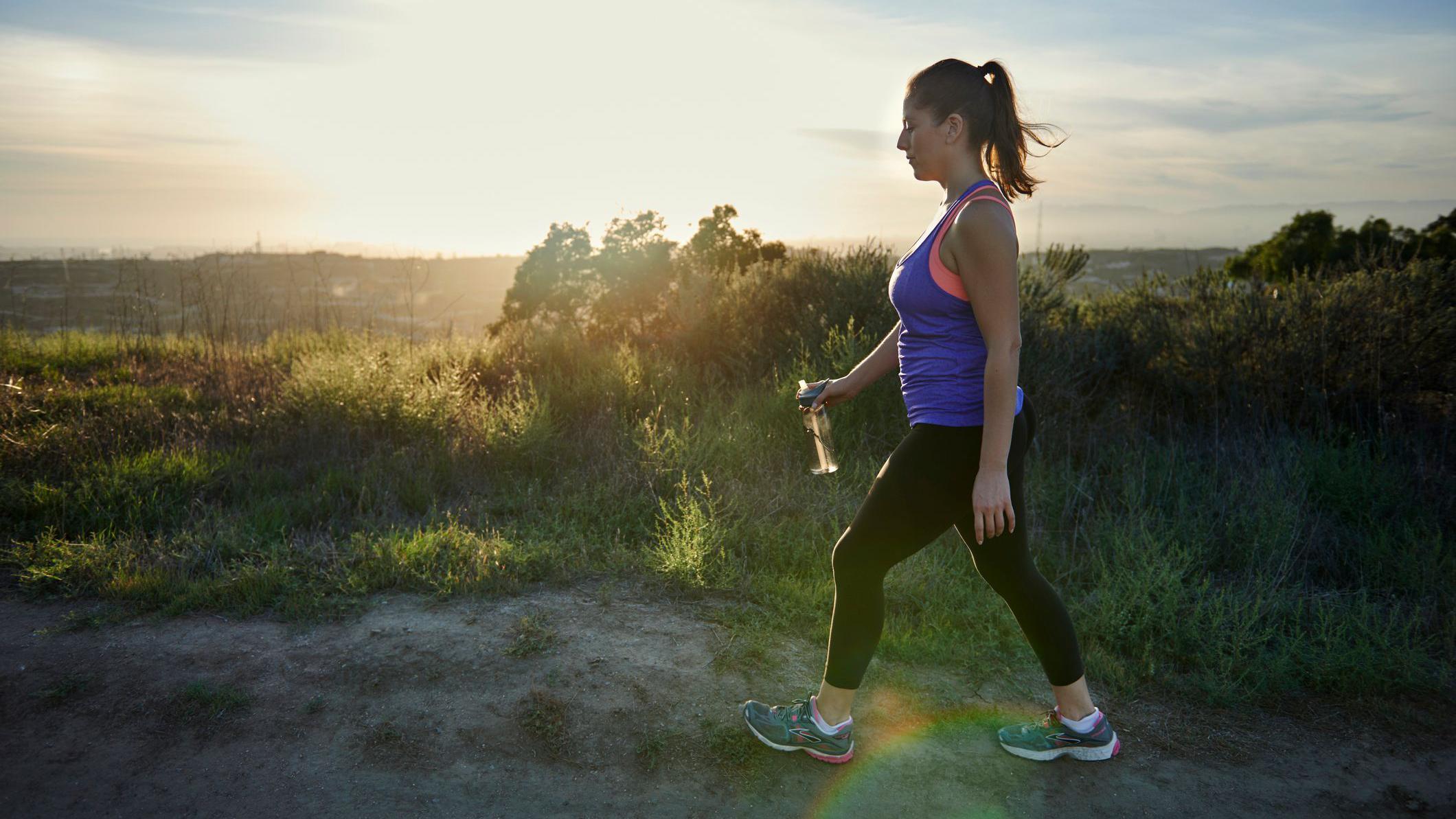 Da biste čuvali zdravlje dovoljno je i 7.000 koraka dnevno, ukazuje studija 3 Žena u ljubičastoj majici i crnim helankama šeta selom. Kosa joj je vezana i drži flašicu vode.