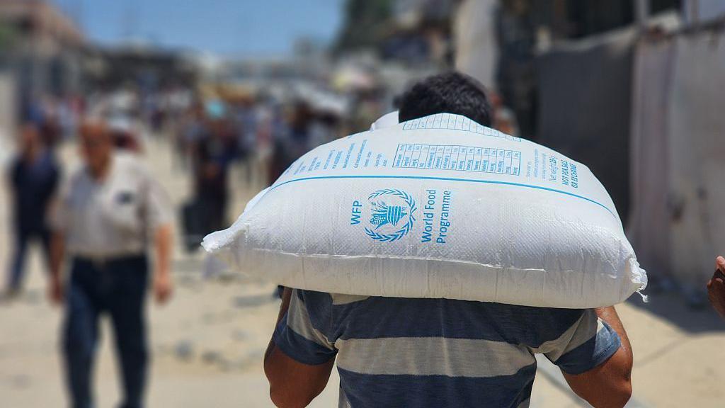 A Palestinian man carries a sack of flour.
