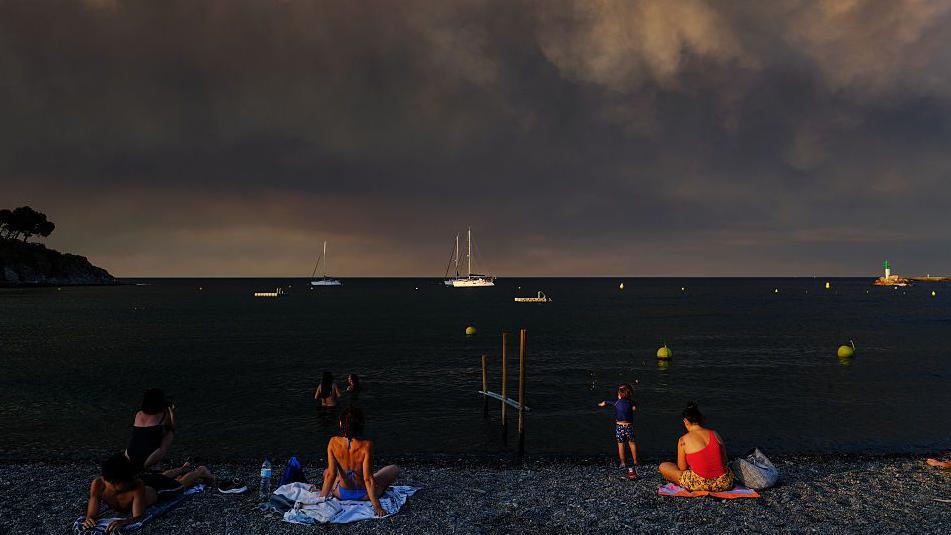 U požarima u Francuskoj izgorela površina veća od Pariza: 'Katastrofa' 6 Turisti na plaži na jugu Francuske dok se gust dim izdiže iznad mora