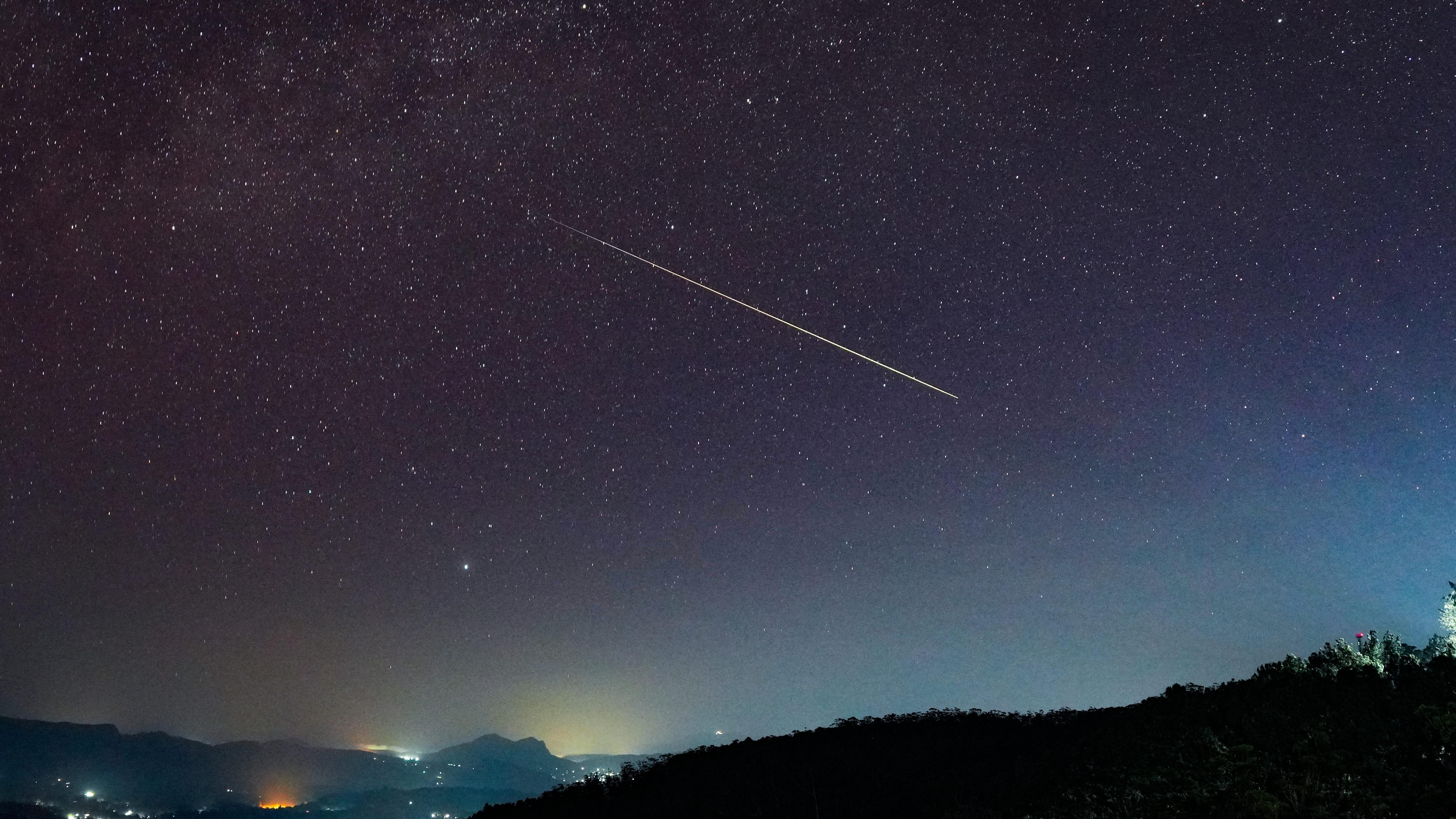 Kako gledati Perseide - 'meteorsku kišu godine' 5 Veliki Perseid meteor dijagonalno prelazi zvezdano noćno nebo iznad Haputala, Šri Lanka - u prvom planu se vide tamna brda sa svetlima zgrada