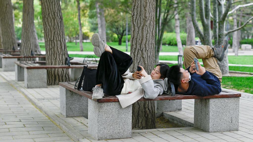 Kako veštačka inteligencija pruža emotivnu podršku mladima 1 A Chinese couple use their mobile phones while sharing a bench at a park in Beijing on 21 April 2021
