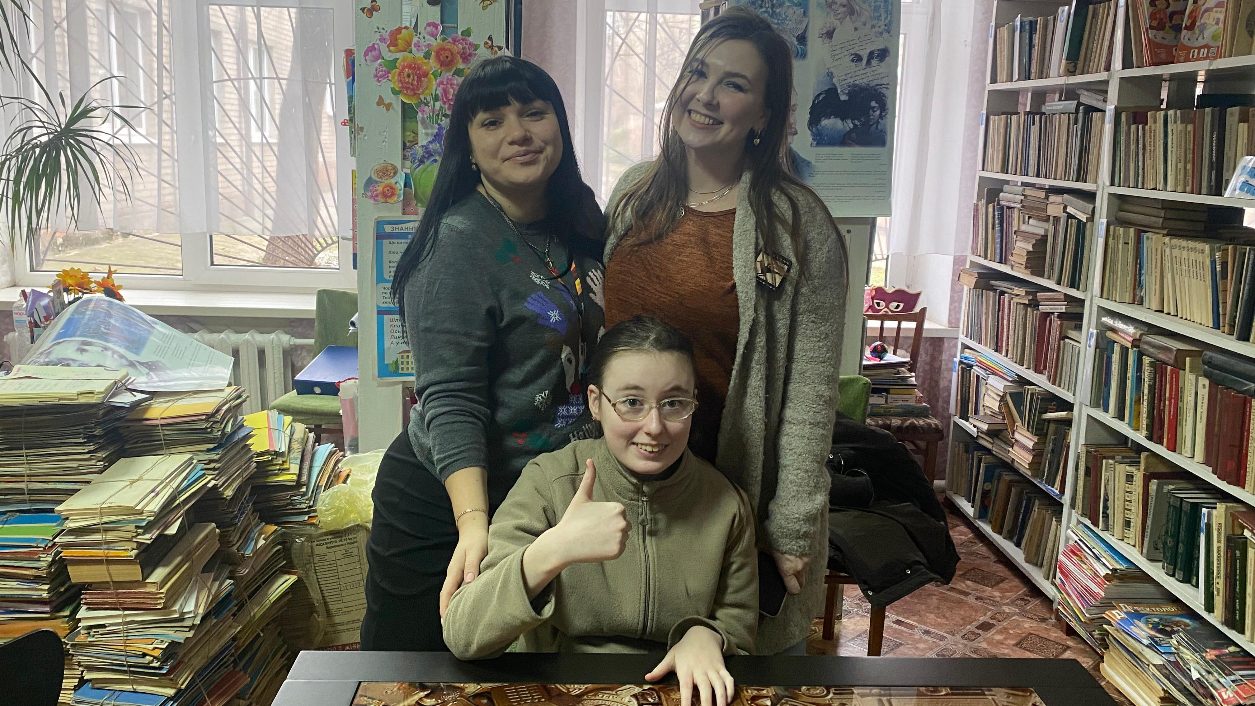 Kako se deca sa invaliditetom nose sa ratom u Ukrajini 3 Jeva Pavlova sedi, a dve žene stoje i drže je za ramena