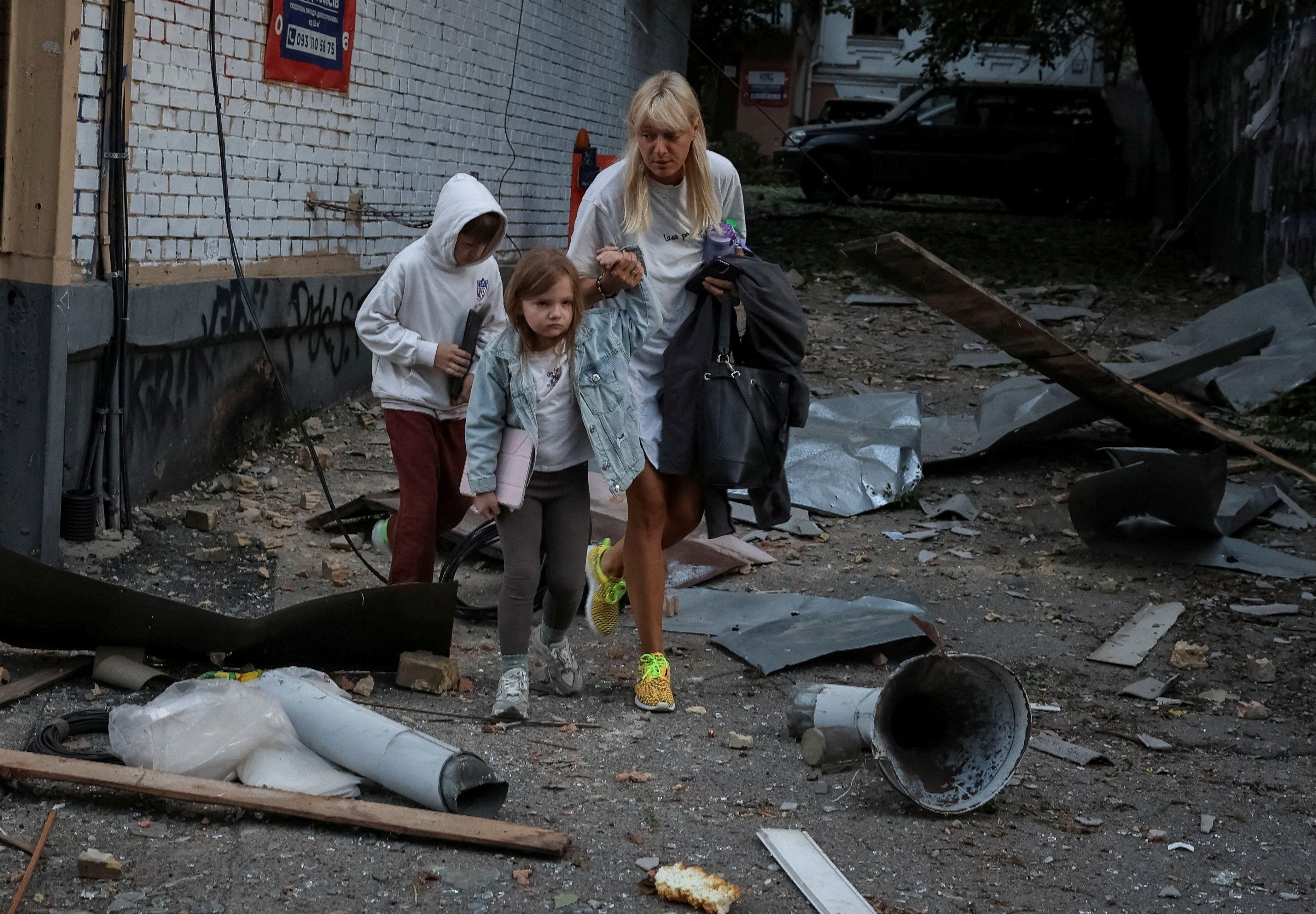 ruski napad na Kijev, ćena sa dvoje dece hoda među ruševinama posle ruskog napada na Kijev