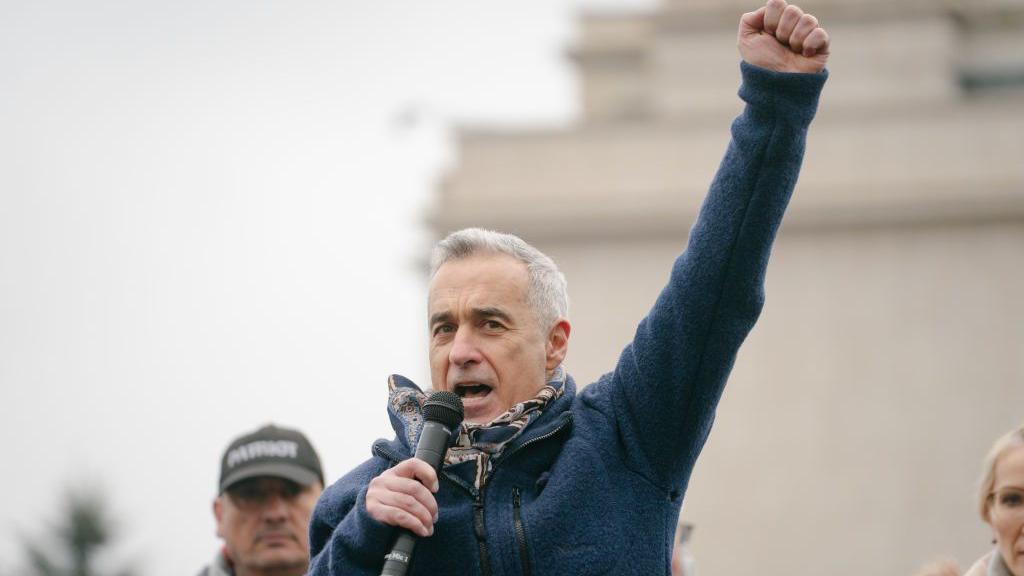 Kalin Đorđesku u teget jakni sa podignutom rukom govori na mitingu