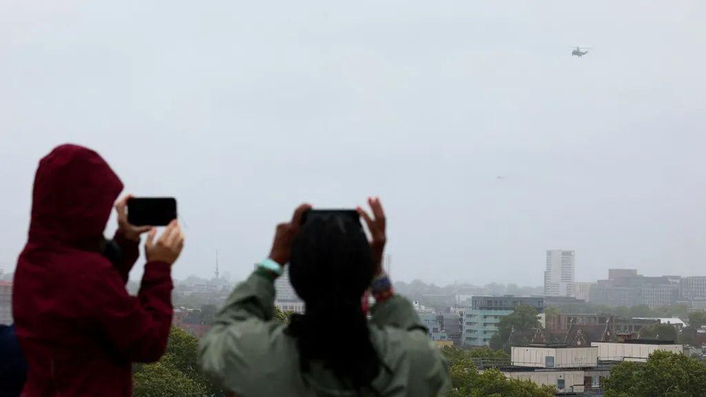Melanija i Donald Tramp u Vindzoru: Kraljevski doček i vožnja kočijama - u fotografijama 9 Dvoje prolaznika telefonima slika helikopter Marinac jedan dok leti ka Vindzor zamku