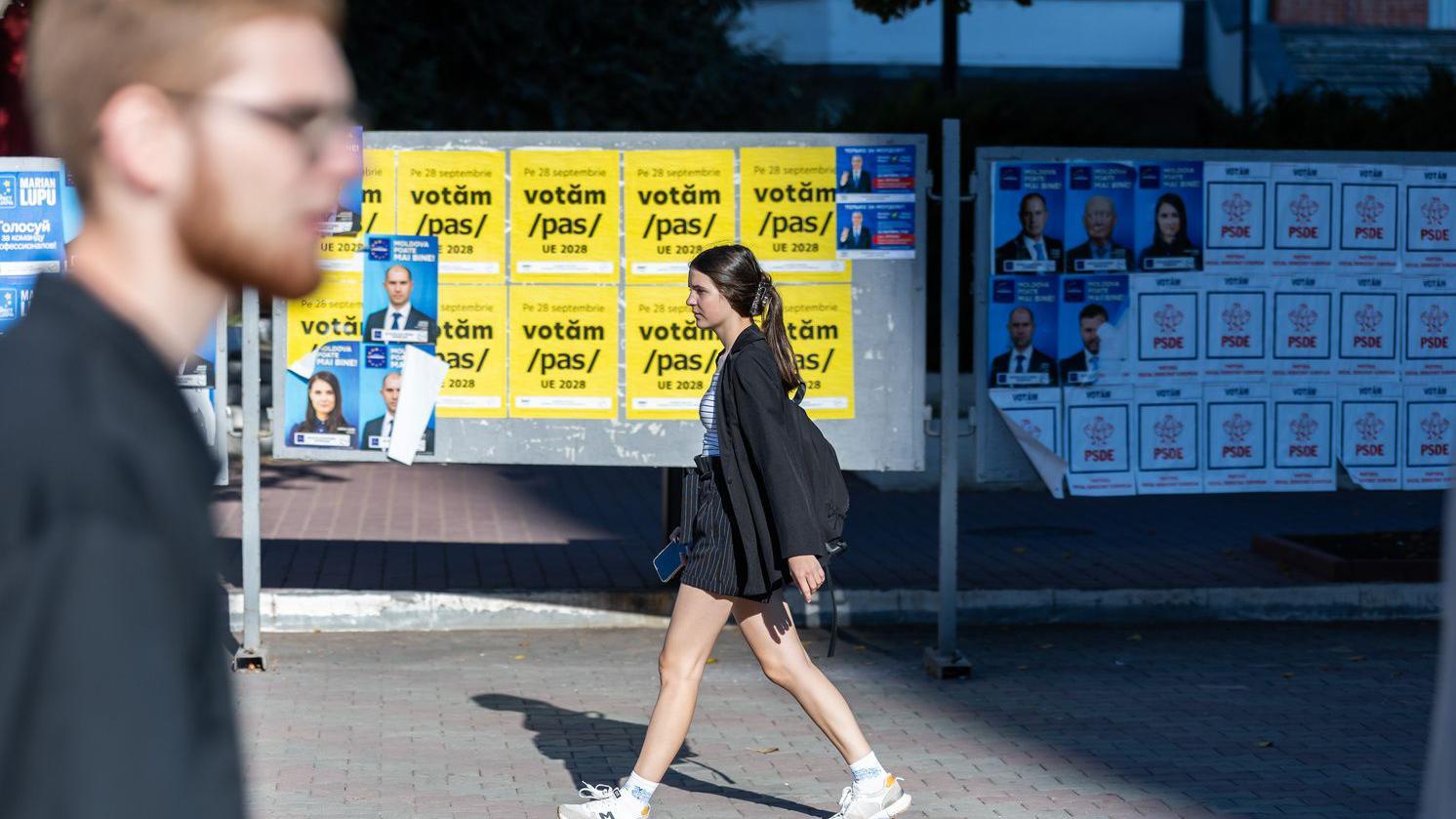 Rusi obučavali Moldavce u Srbiji da 'izazivaju nerede' u susret izborima, tvrdi moldavsko tužilaštvo 4 Devojka hoda ulicom pored bilborda na kojima su politički plakata koji pozivaju na predstojeće izbore