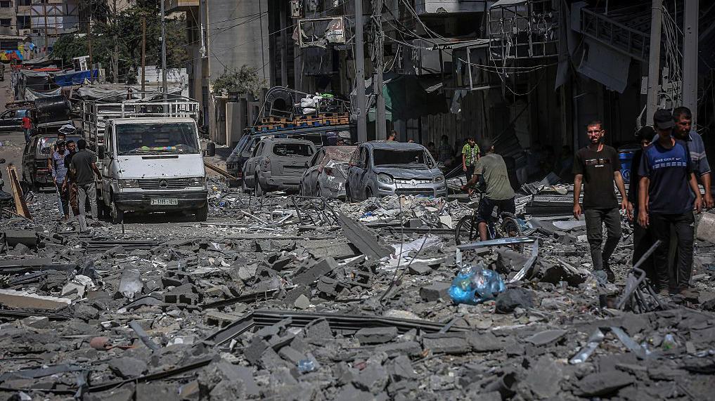 'Eksplozivna gvozdena čudovišta': Stanovnici Gaze strahuju od izraelskih navođenih 'robota' 1 Ulica u naselju Rimal u gradu Gazi je prekrivena ruševinama. Mnogo uništenih automobila može se videti duž ulica dok se ljudi okupljaju u malim grupama.