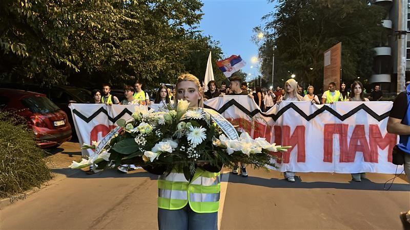 Devojka nosi cveće ispred kolone