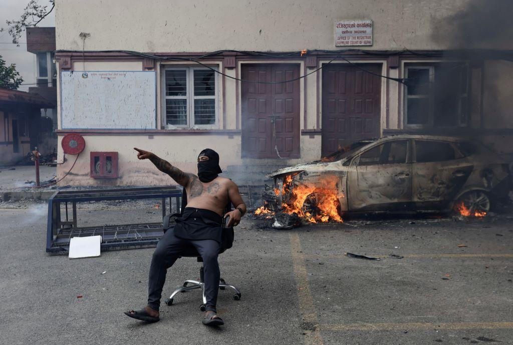 Nepal: Vojska uspostavila mir, prva žena premijer u istoriji zemlje 14 Demonstrant sa maskom preko lica i bez majice sedi ispred auta koji gori