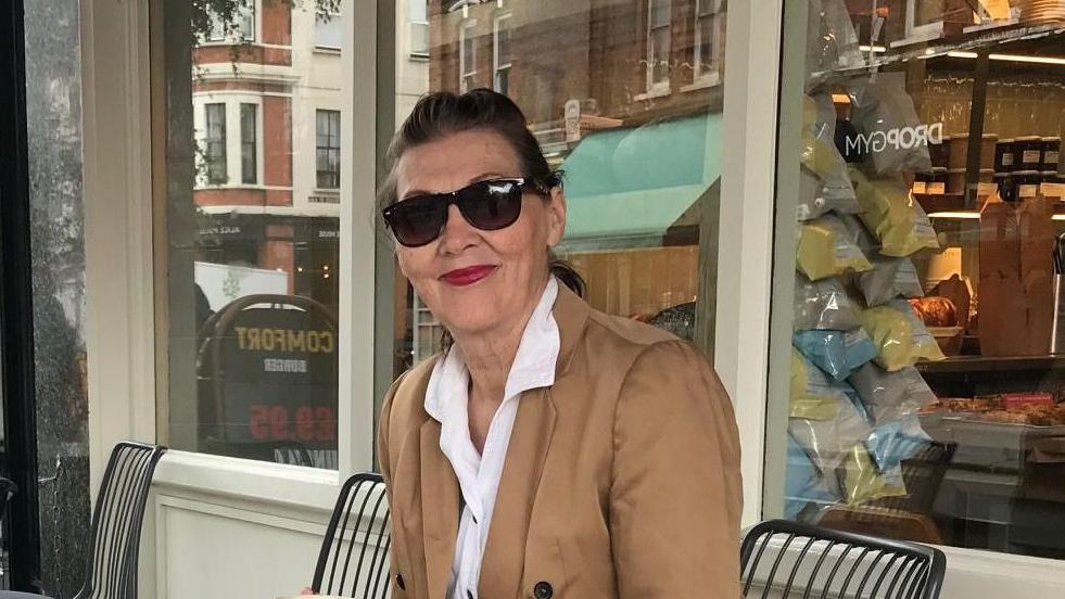 Žena sa sunčanim naočarama sedi na stolici 