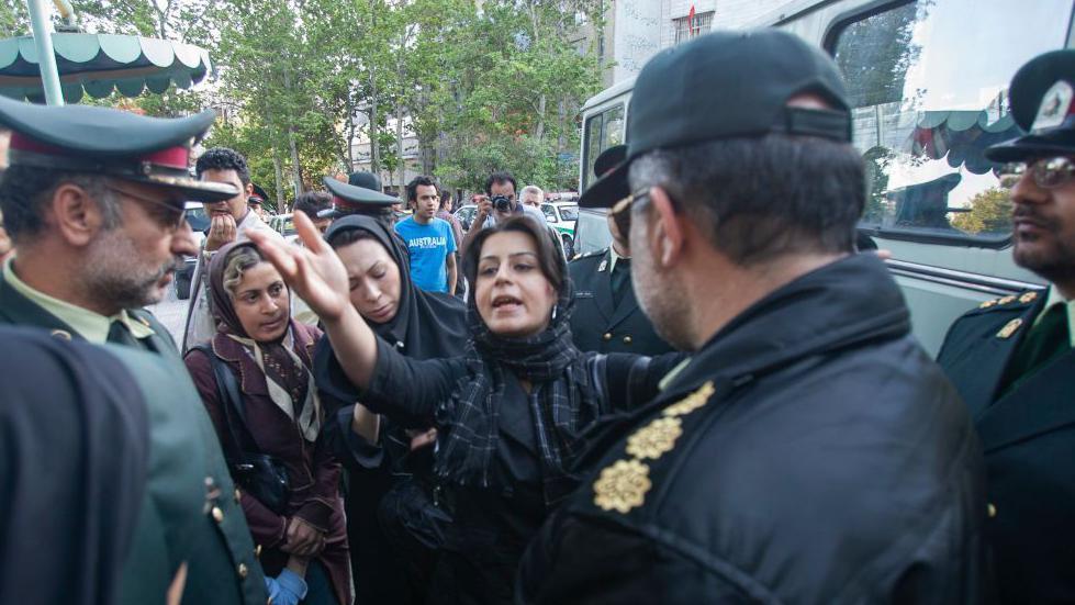 Pramen kose i talas besa: Šta se stvarno promenilo u Iranu posle protesta 'Žena, život, sloboda' 4 Policija gleda u ženu koja je podigla ruku i objašnjava dok iza nje stoje dve žene i okupljeni muškarci