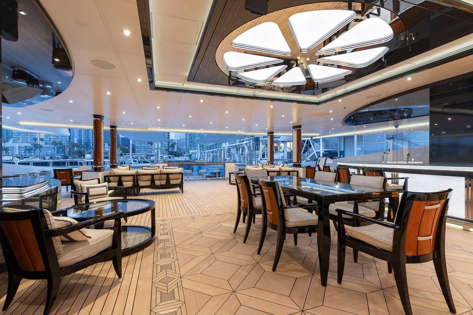 'Beskonačni' bazen, helidrom, osam soba: 'Superjahta ruskog milijardera' na aukciji 3 Soba unutar superjahte Amadea ima drvene podove i stolice sa bež jastucima, zajedno sa odgovarajućim sofama. Gradski pejzaž se vidi kroz prozore u pozadini.