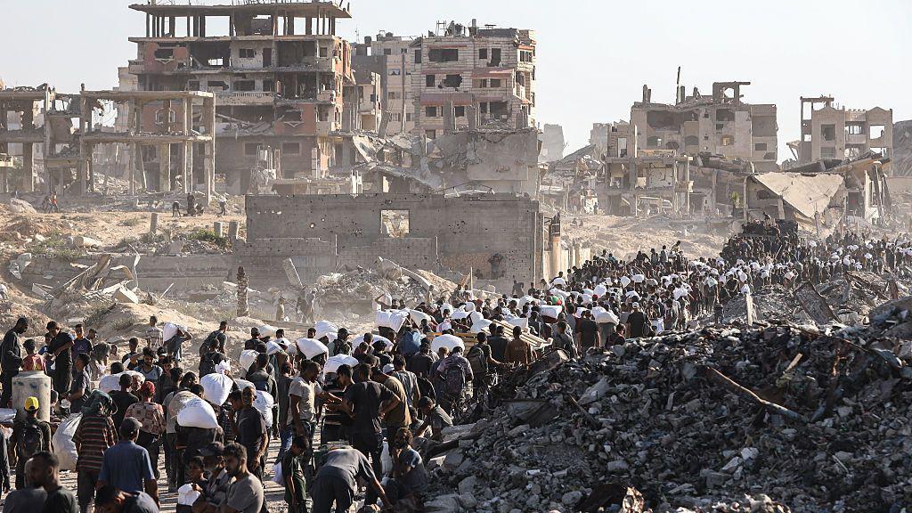 Šta je genocid 1 Ljudi u Gazi hodaju sa džakovima na leđima pored razrušenih zgrada