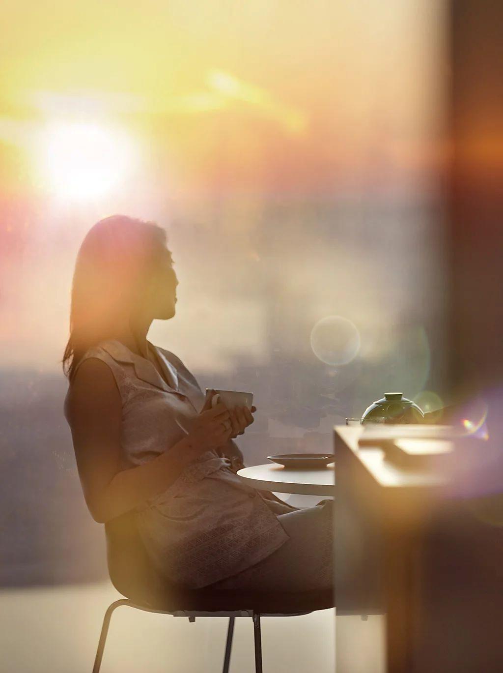 Manje kafe, živopisniji snovi 2 žena drži šoljicu kafe sa obe ruke i gleda levo od sebe