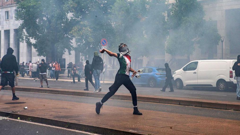 Sukobi demonstranata i policije na skupovima podrške Palestincima u Italiji 3 Mladić lica prekrivenog maramom baca kamen