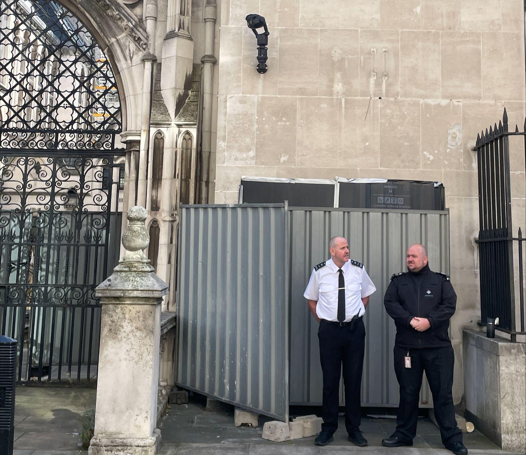 Novi Benksijev mural uklonjen sa zida suda u Londonu 2 Dvojica članova obezbeđenja stoje ispred metalnih barijera iza kojih je Benksijev mural