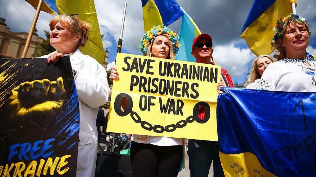 'Tamo vas ubijaju polako': Ukrajinski zarobljenici o ozloglašenom ruskom zatvoru 2 Ljudi drže transparente na kojima zahtevaju oslobađanje ukrajinskih ratnih zarobljenika, na jednom od njih piše „Slobodna Ukrajina“