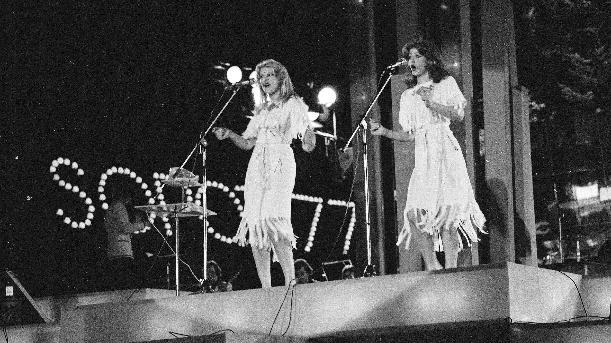 Dve devojke u belim haljinama na bini