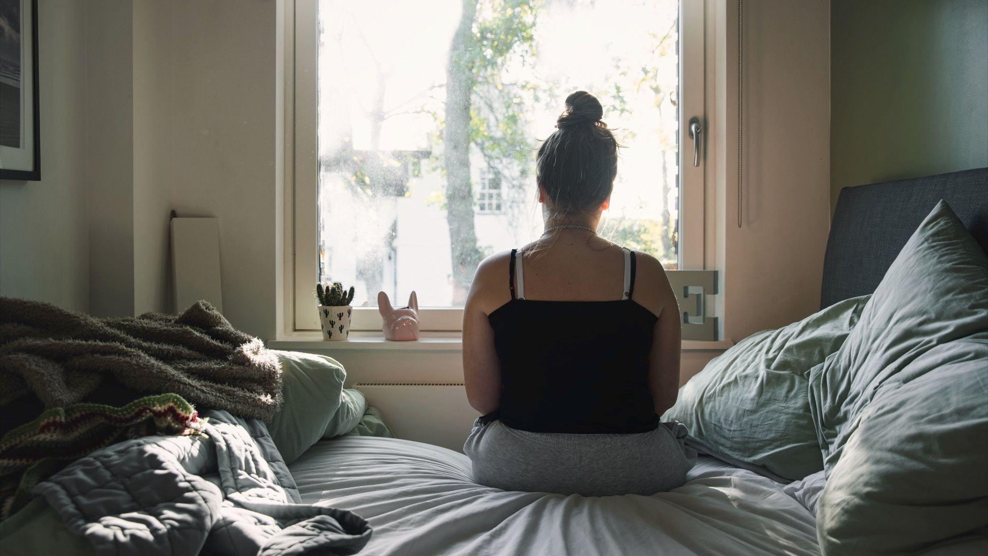 Kako sačuvati zdravo srce 4 Tinejdžerka gleda kroz prozor dok sedi na krevetu u majici na bretele