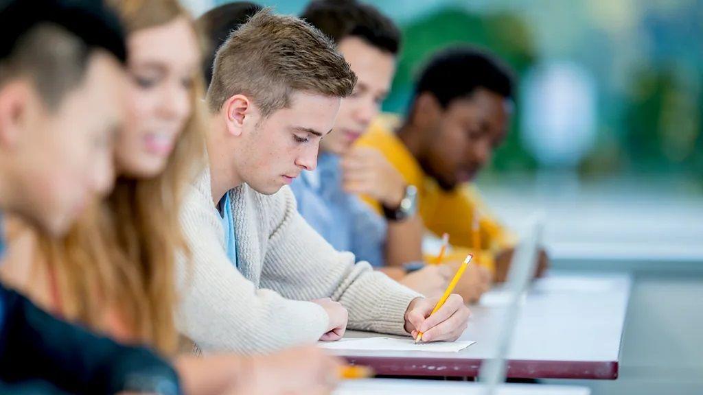 Kad je najbolje beleške hvatati rukom 1 Muškarac piše rukom za stolom među drugim ljudima