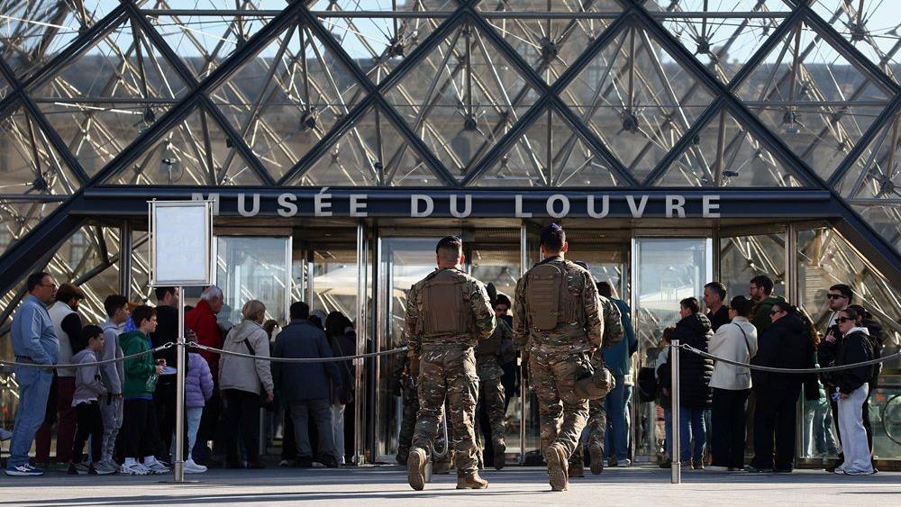 Da li je 50 godina star matematički problem mogao da spase Luvr od pljačke 1 muzej luvr, pljačka u luvru, opljačkan muzej luvr, Francuski vojnici iz bezbednosnog plana „Sentinel“ patroliraju pored staklene piramide dok ljudi čekaju u redu za ulazak u muzej Luvr